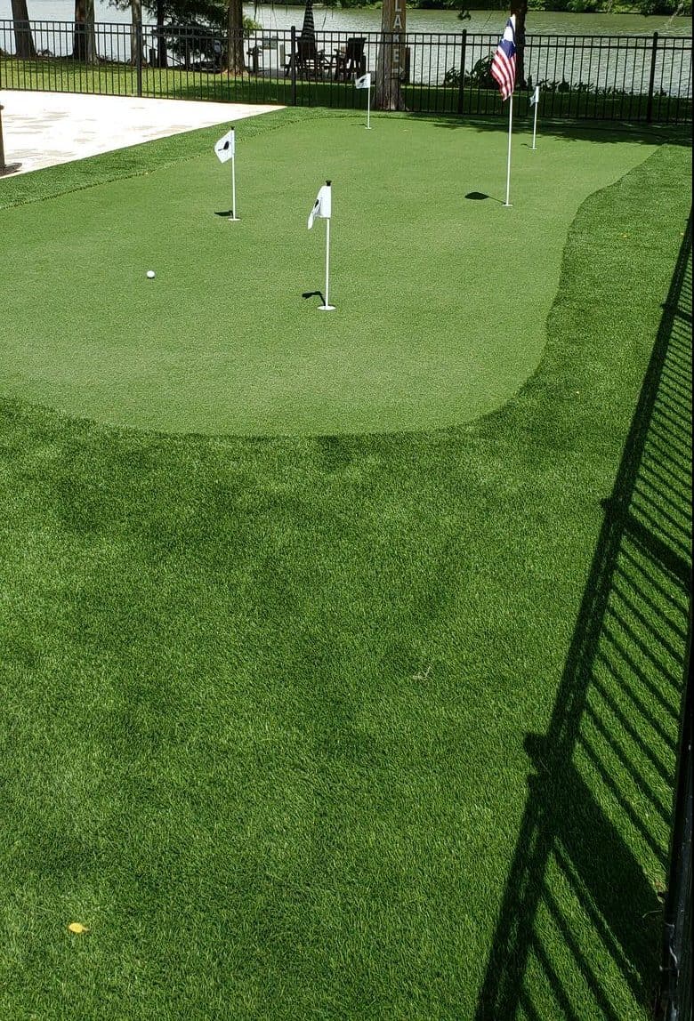 Professional artificial turf putting green installed in Lake Jackson Houston, around synthetic grass backyard landscaping.